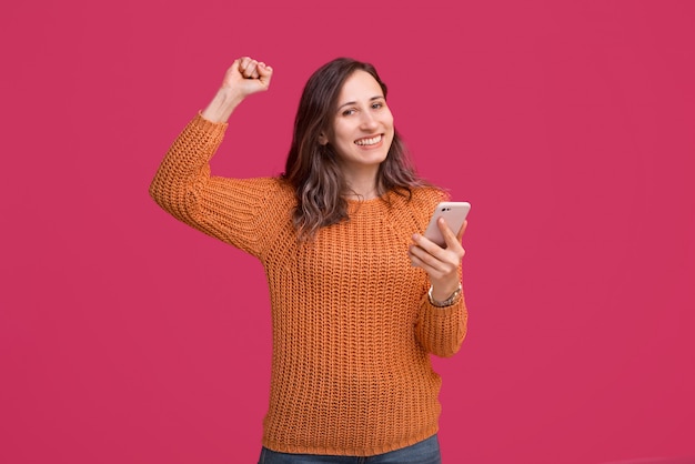 Heureuse belle femme à l'aide de smartphone et célébrer la victoire