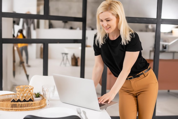 Heureuse belle femme décontractée travaillant sur un ordinateur portable assis dans la maison.