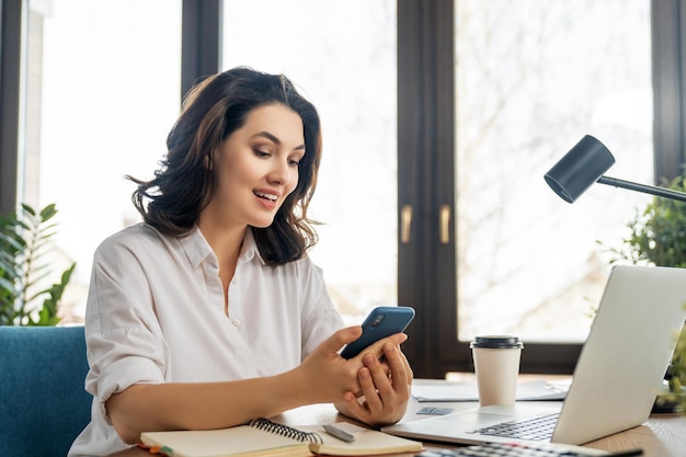 Heureuse belle femme décontractée travaillant sur un ordinateur portable au bureau