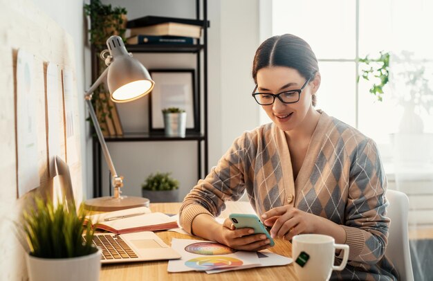 Heureuse belle femme décontractée travaillant sur un ordinateur portable à la maison.