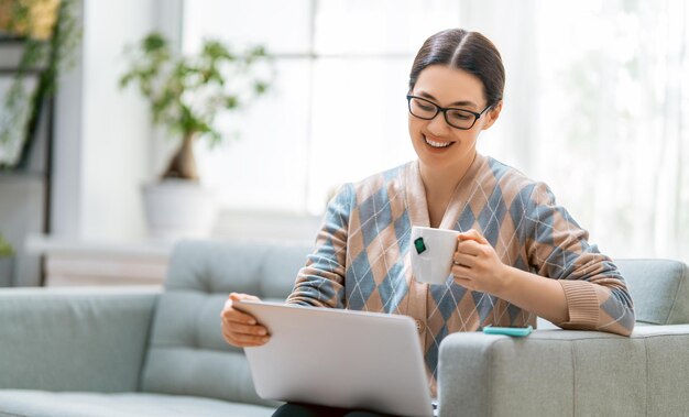 Heureuse belle femme décontractée travaillant sur un ordinateur portable à la maison.