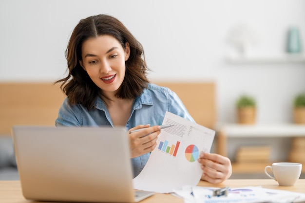 Heureuse belle femme décontractée travaillant sur un ordinateur portable à la maison.