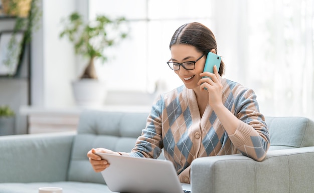 Heureuse belle femme décontractée travaillant sur un ordinateur portable à la maison.