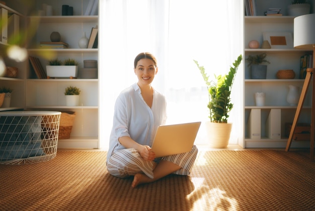 Heureuse belle femme décontractée utilisant un ordinateur portable à la maison