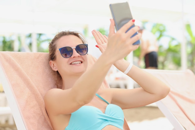 Heureuse belle femme en maillot de bain fait un selfie