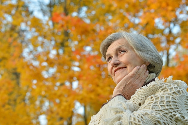 Heureuse belle femme senior dans le parc en automne