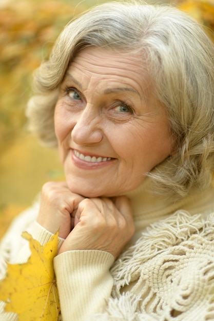 Heureuse belle femme senior dans le parc en automne