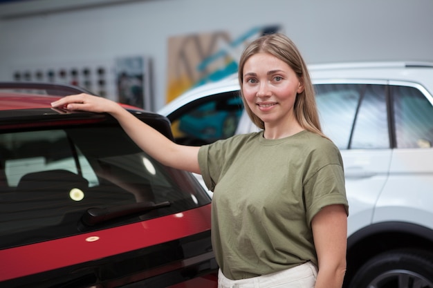 Photo heureuse belle femme souriante à la caméra après avoir acheté une nouvelle voiture chez le concessionnaire