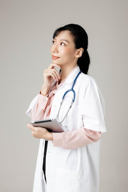 Heureuse belle femme de travail asiatique en vêtements de bureau souriant et sur fond isolé gris