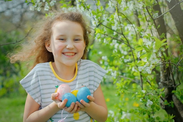 Heureuse belle fille détient des oeufs colorés le jour de Pâques. l'enfant sourit et attend des cadeaux. concept de pâques, vacances et enfant