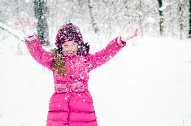 Heureuse belle fille enfant profiter de la neige à l&#39;extérieur dans le parc forestier d&#39;hiver. Joyeuse petite fille