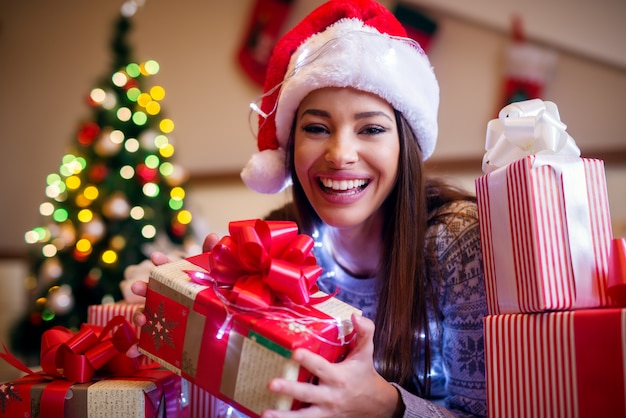 Heureuse belle jeune femme avec chapeau de Noël et présente autour.