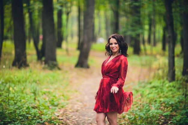 Heureuse belle jeune femme danse de la liberté dans le parc d'été avec des arbres en arrière-plan. Parc du Palais d'été.