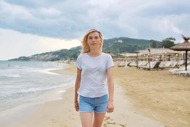 Heureuse belle jeune femme marchant sur la plage