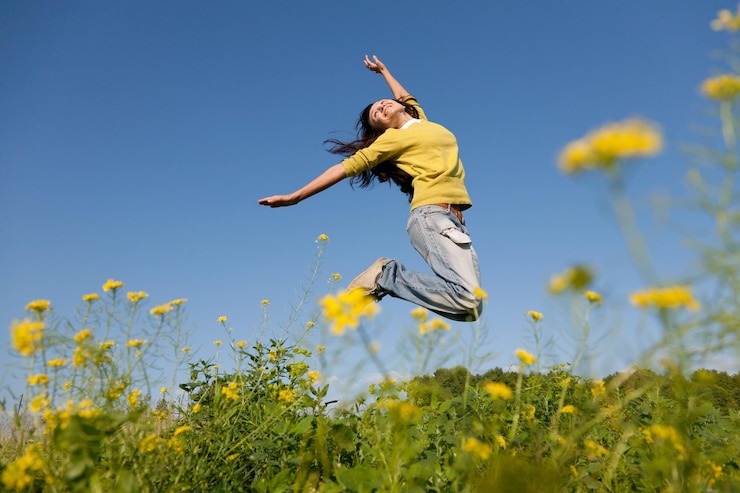 Photo heureuse et belle jeune fille sautant haut dans un champ d'été