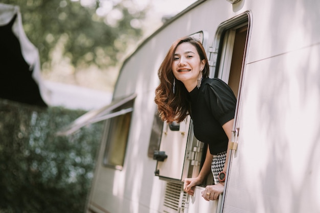 Heureuse belle jolie femme asiatique par la fenêtre du camping-car