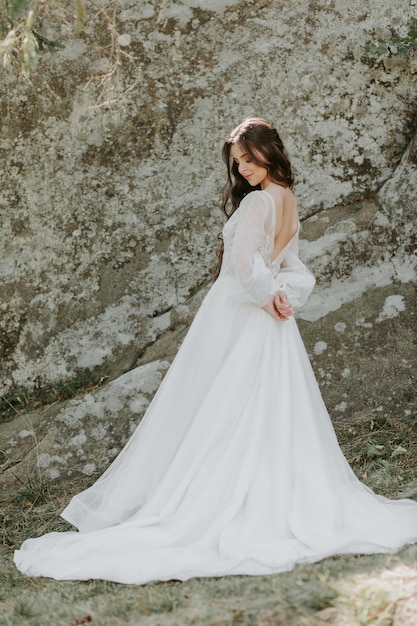 Heureuse belle mariée à l'extérieur sur une prairie d'été au coucher du soleil avec une vue parfaite