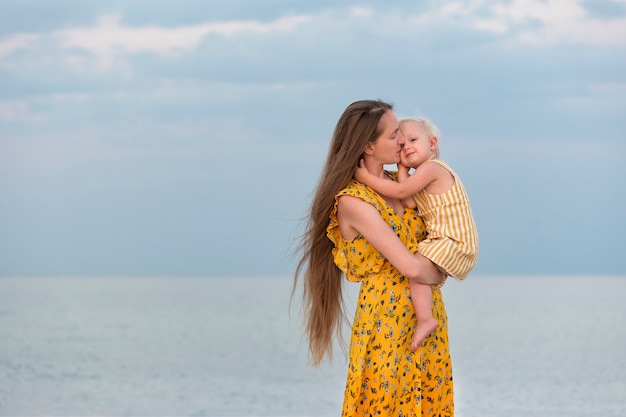 Heureuse belle mère énorme bébé près de la mer. Mère et fille.