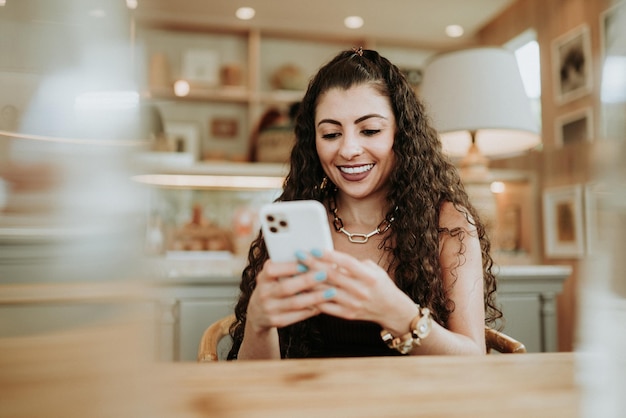 Heureuse dame latine se détendre seule à la maison pose partager de bonnes nouvelles sur les réseaux sociaux via un téléphone portable.