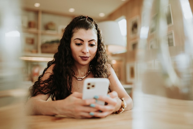 Heureuse dame latine se détendre seule à la maison pose partager de bonnes nouvelles sur les réseaux sociaux via un téléphone portable.