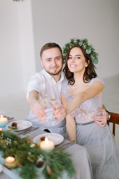 Heureuse demoiselle d'honneur et groomman à la table de mariage boivent du champagne