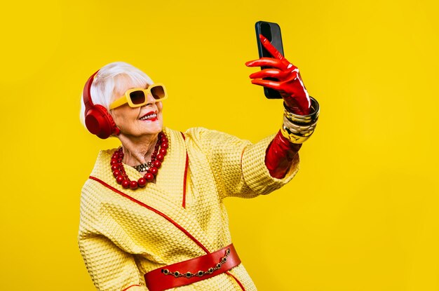 Heureuse et drôle vieille dame cool avec des vêtements à la mode portrait sur fond coloré Jeune grand-mère avec des concepts de style extravagants sur l'ancienneté de style de vie et les personnes âgées