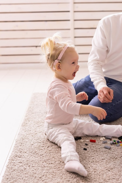 Heureuse enfant fille avec implant cochléaire s'amusant avec son père appareil auditif pour concept de technologie de santé sourd et innovant