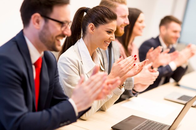 Heureuse équipe d&#39;affaires souriant frappant des mains lors d&#39;une réunion