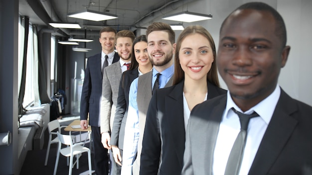 Photo heureuse équipe commerciale souriante debout dans une rangée au bureau.