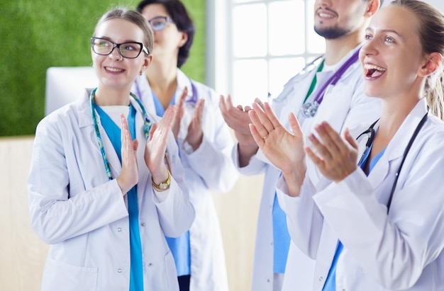 Heureuse équipe médicale composée de médecins masculins et féminins souriant largement et donnant un coup de pouce de succès et d'espoir