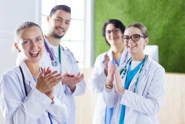 Heureuse équipe médicale composée de médecins masculins et féminins souriant largement et donnant un coup de pouce de succès et d'espoir