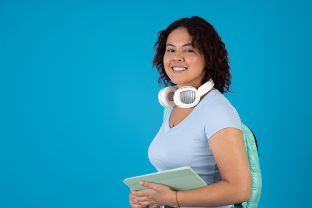 Heureuse étudiante portant une tablette numérique et un casque blanc