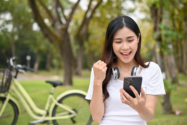 Heureuse et excitée jeune femme asiatique recevant de bonnes nouvelles sur le texte