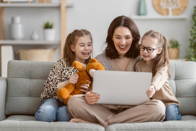 Heureuse famille aimante Jeune mère et filles filles utilisant un ordinateur portable Maman drôle et beaux enfants