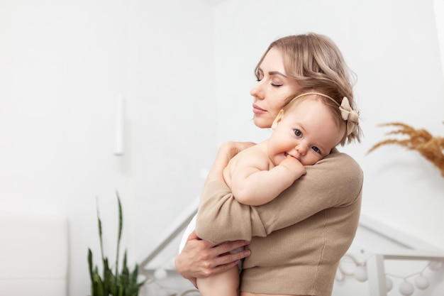 Heureuse famille aimante Une mère attentionnée embrasse sa petite fille assise sur le lit dans la chambre