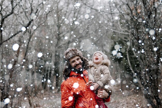 Heureuse famille aimante Père et son bébé jouent et s'embrassent à l'extérieur Petit enfant et papa sur une promenade d'hiver enneigée dans la nature Concept de la première chute de neige d'hiver tant attendue