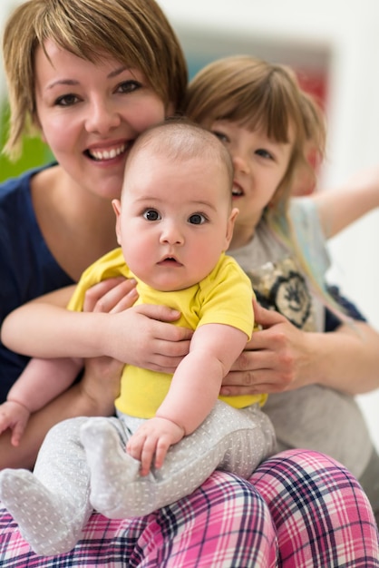 Heureuse famille aimante. portrait de jeune mère avec ses enfants petite fille et bébé garçon se serrant les coudes tout en passant du temps ensemble à la maison