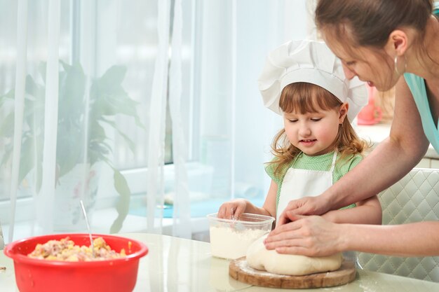 Heureuse famille aimante préparant la boulangerie ensemble. Maman enseigne à l'enfant comment cuisiner