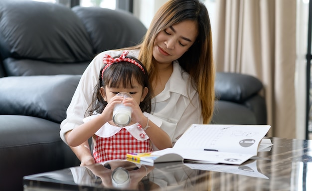 Heureuse famille asiatique maman et fille boivent du lait à la maison