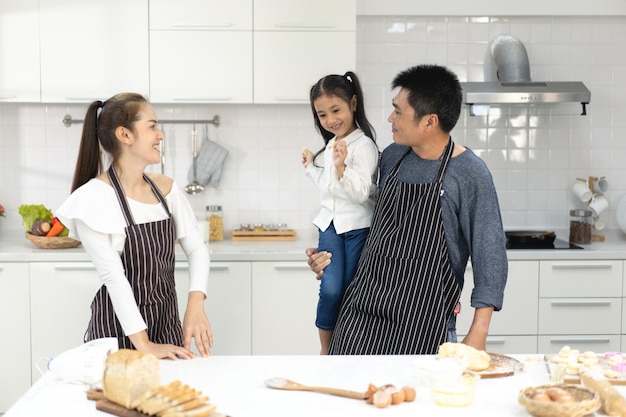 Photo heureuse famille asiatique avec sa fille faisant de la pâte à préparer des biscuits la fille aide le parent à préparer le concept de famille de cuisson