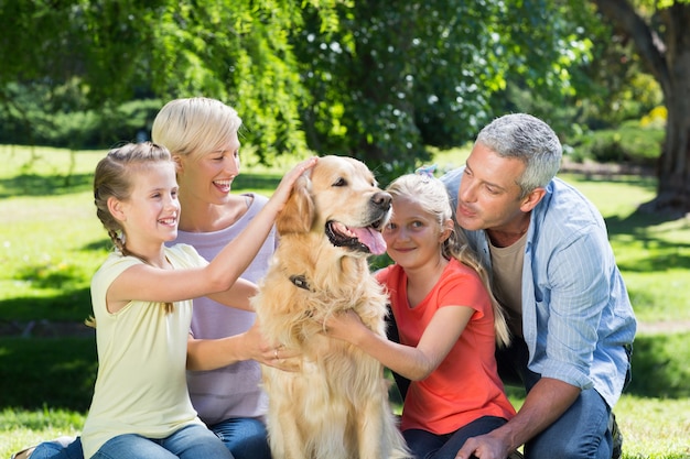 Heureuse famille caresser leur chien dans le parc