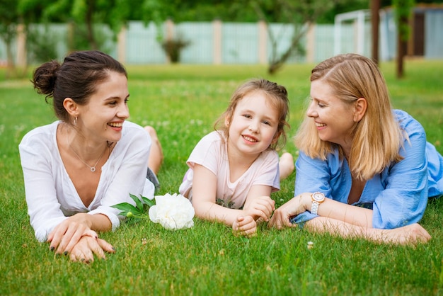 Heureuse famille caucasienne de trois générations allongée sur l'herbe ensemble dans la mère du parc