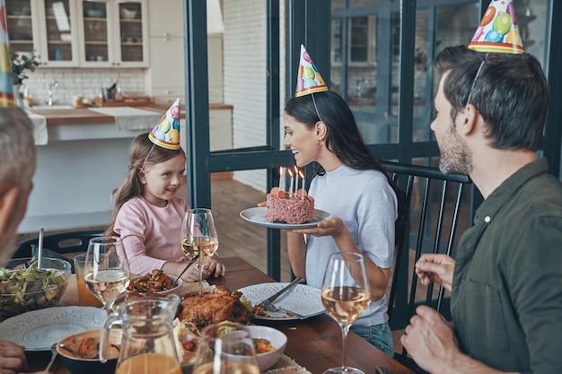 Heureuse famille célébrant l'anniversaire de la petite fille assise à la table à manger à la maison