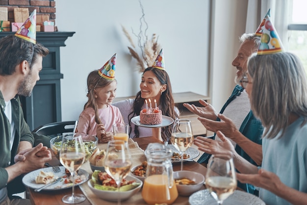 Heureuse famille célébrant l'anniversaire de la petite fille assise à la table à manger à la maison