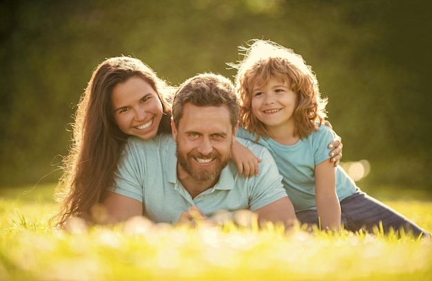 Heureuse famille de maman papa et fils enfant se détendre dans le parc d'été herbe verte liaison familiale