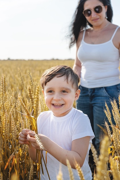 Heureuse famille de mère et enfant en bas âge marchant sur le champ de blé