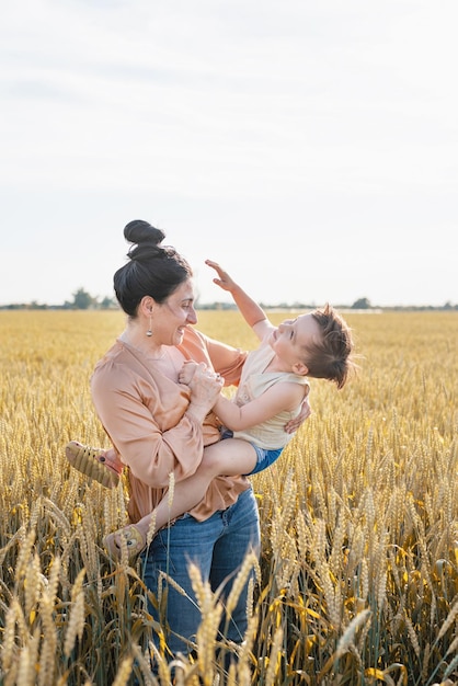 Heureuse famille de mère et enfant en bas âge marchant sur le champ de blé