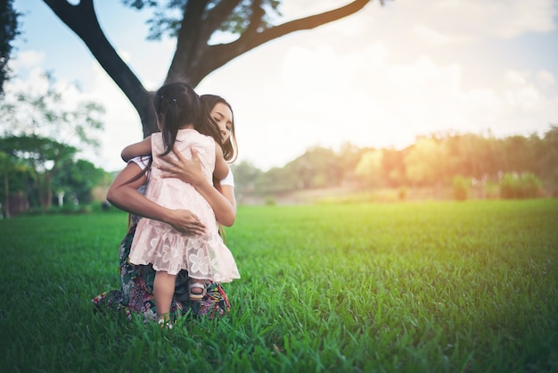 Heureuse famille mère étreindre fille et jouer dans le parc