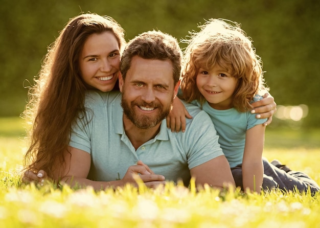 Heureuse famille de mère père et fils garçon se détendre dans le parc d'été portrait de famille d'herbe verte