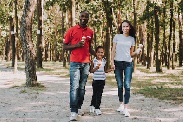 Photo heureuse famille mixte marchant dans le bois.